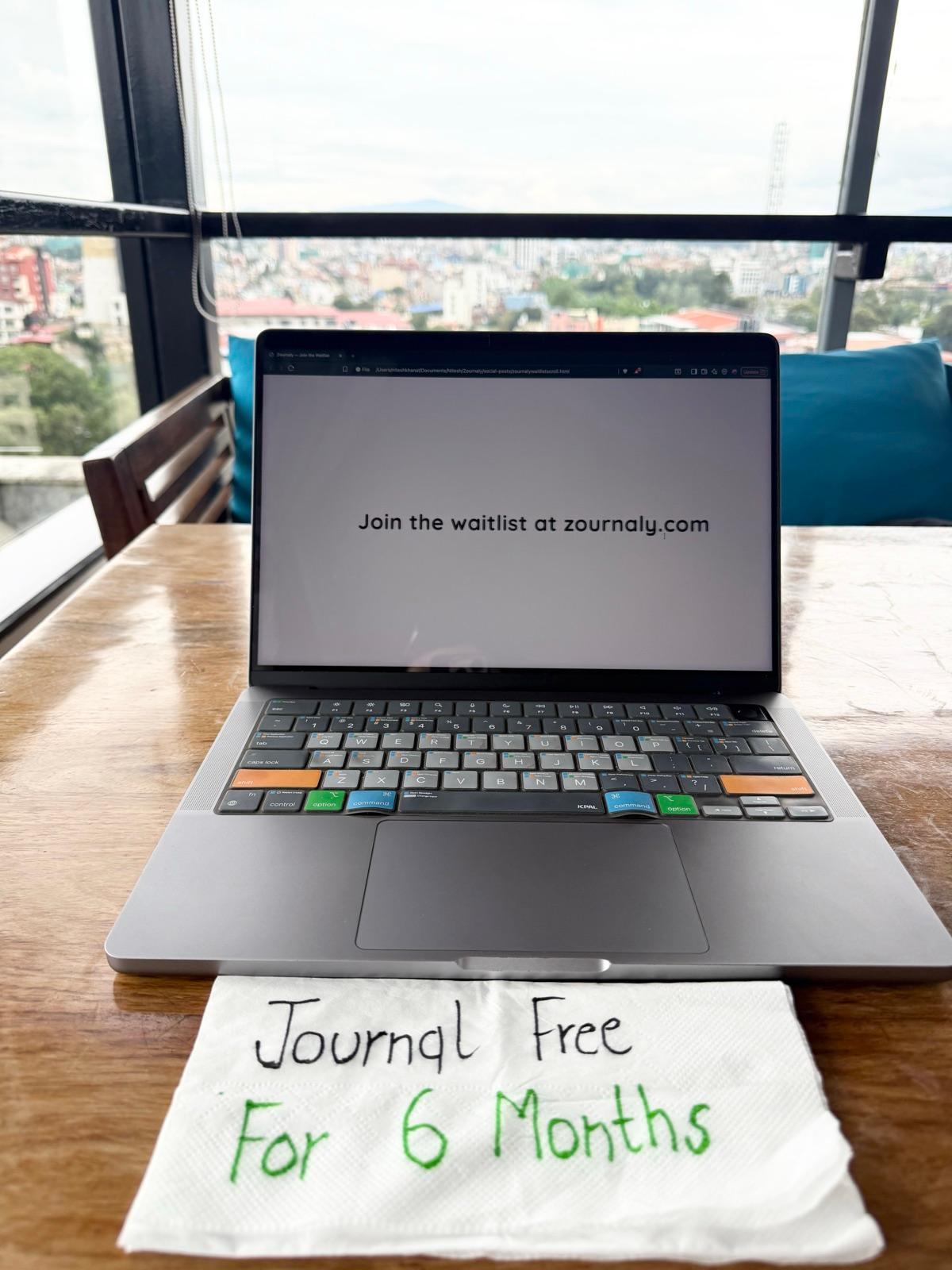 Campaign photo of a laptop showing the Zournaly waitlist beside a handwritten note offering six months free